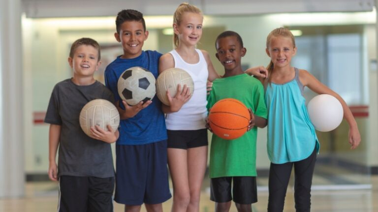 Children hold different sports balls during early training years for professional sports development