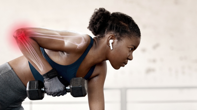 Athlete performing a dumbbell row with elbow pain highlighted, illustrating bone resilience during weight training