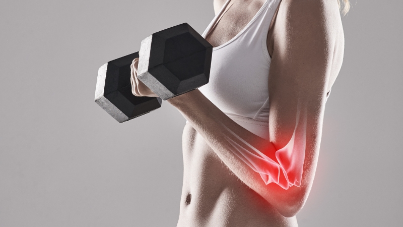 Woman lifting a dumbbell with elbow pain highlighted, showing why bone resilience matters for weight training performance