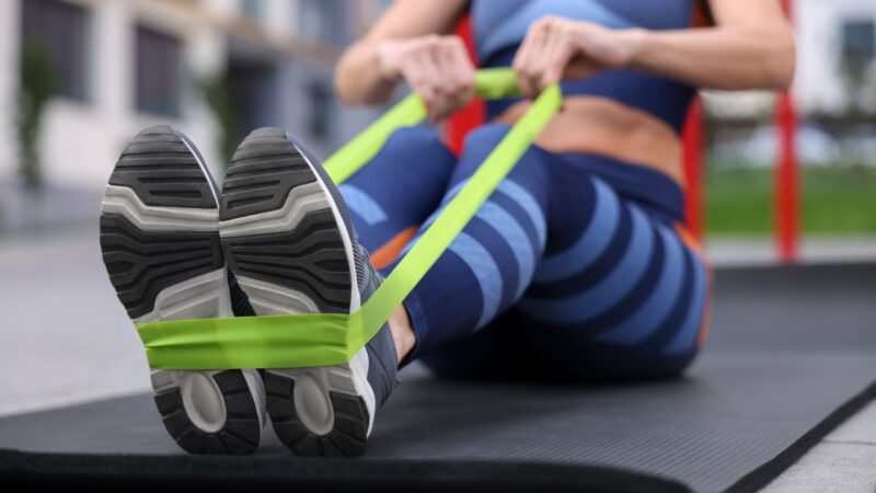 Person using resistance bands for a lower body workout at home with fitness accessories
