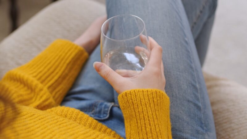 Person sitting on a couch holding a glass of water in the morning