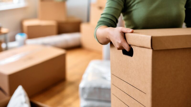 Person lifts a small box with a secure grip to reduce back strain