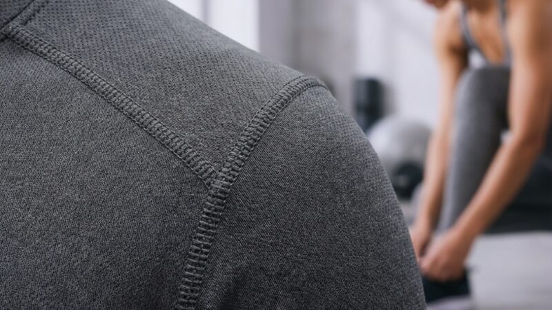 Close-up of gray athletic fabric and person tying shoes