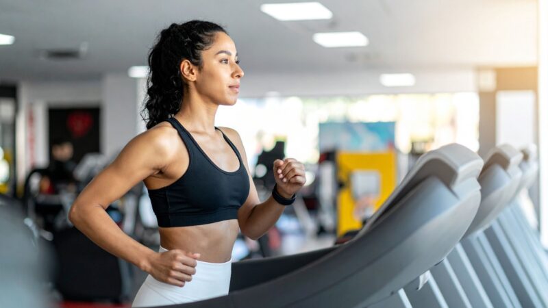 Woman runs on a treadmill in a gym with her hair tied back