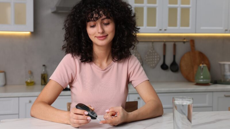 Woman checks blood sugar markers at home before a meal