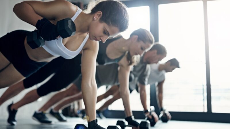 People exercise with dumbbells during a group fitness class