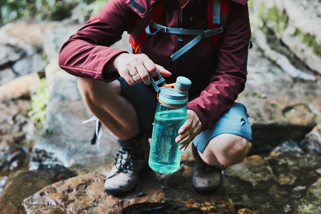 Mountain climber refilling water bottle during hydration and pacing break
