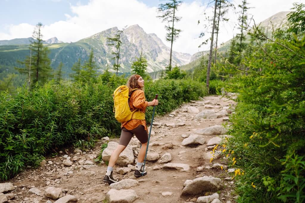 Hiker walking on a rocky mountain trail during beginner climbing preparation