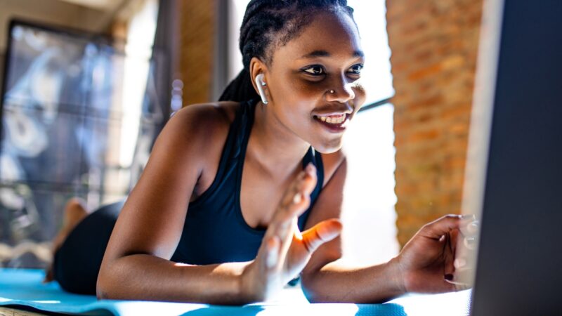 Woman follows an online fitness class on a laptop at home