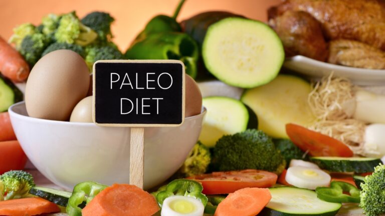 Paleo diet foods with eggs, vegetables, and a small sign on a kitchen table