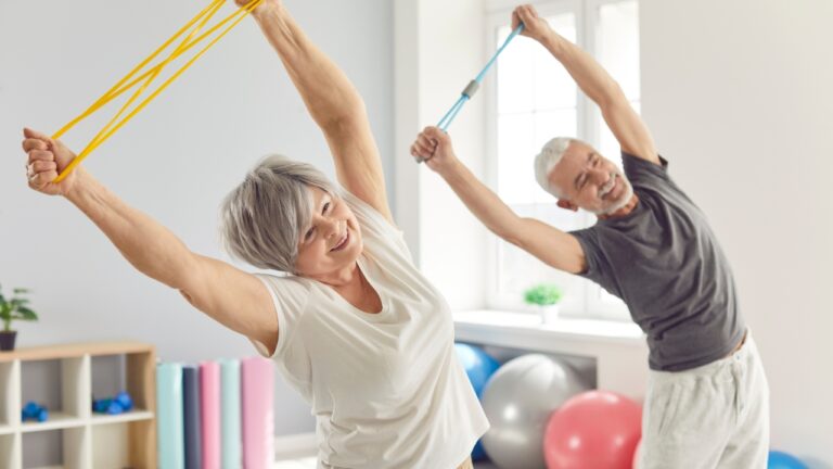 Older adults use resistance bands during safe exercises for seniors in a bright fitness room