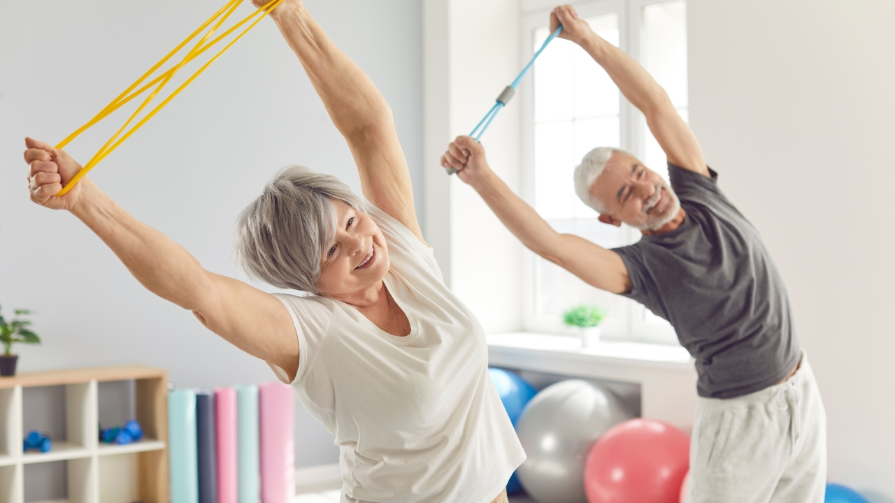 Older adults use resistance bands during safe exercises for seniors in a bright fitness room
