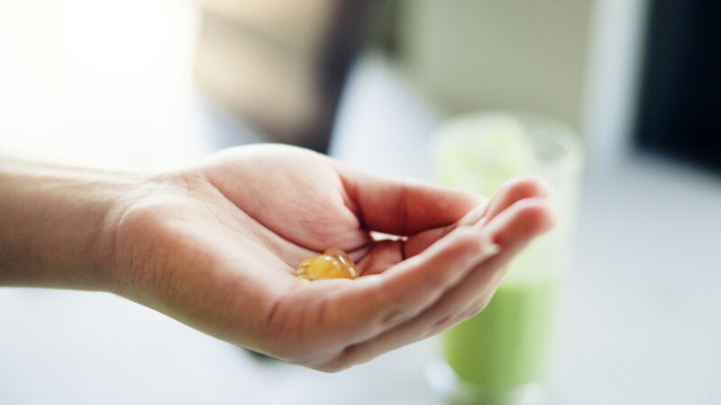 Hand holds a softgel supplement before taking it