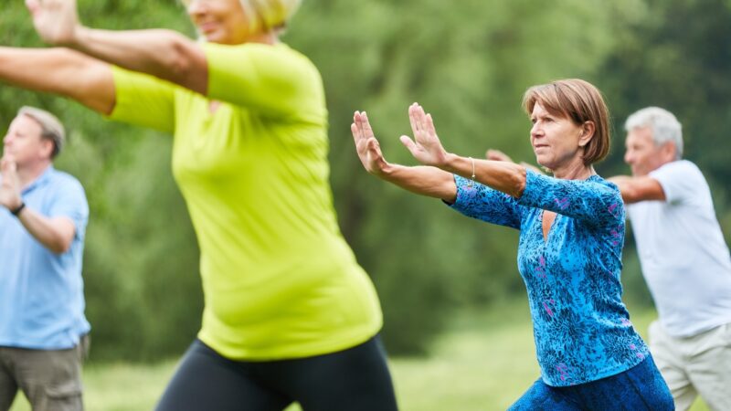 Older adults practice tai chi together in a park