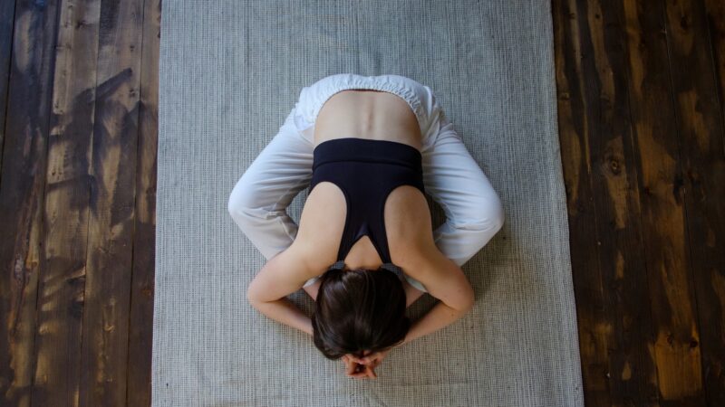 A woman holds a quiet Yin yoga pose on a mat