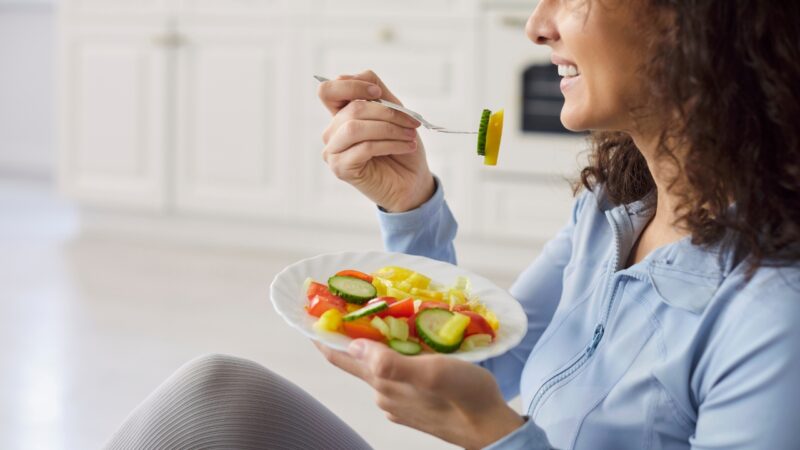 A woman eats a fresh salad at home