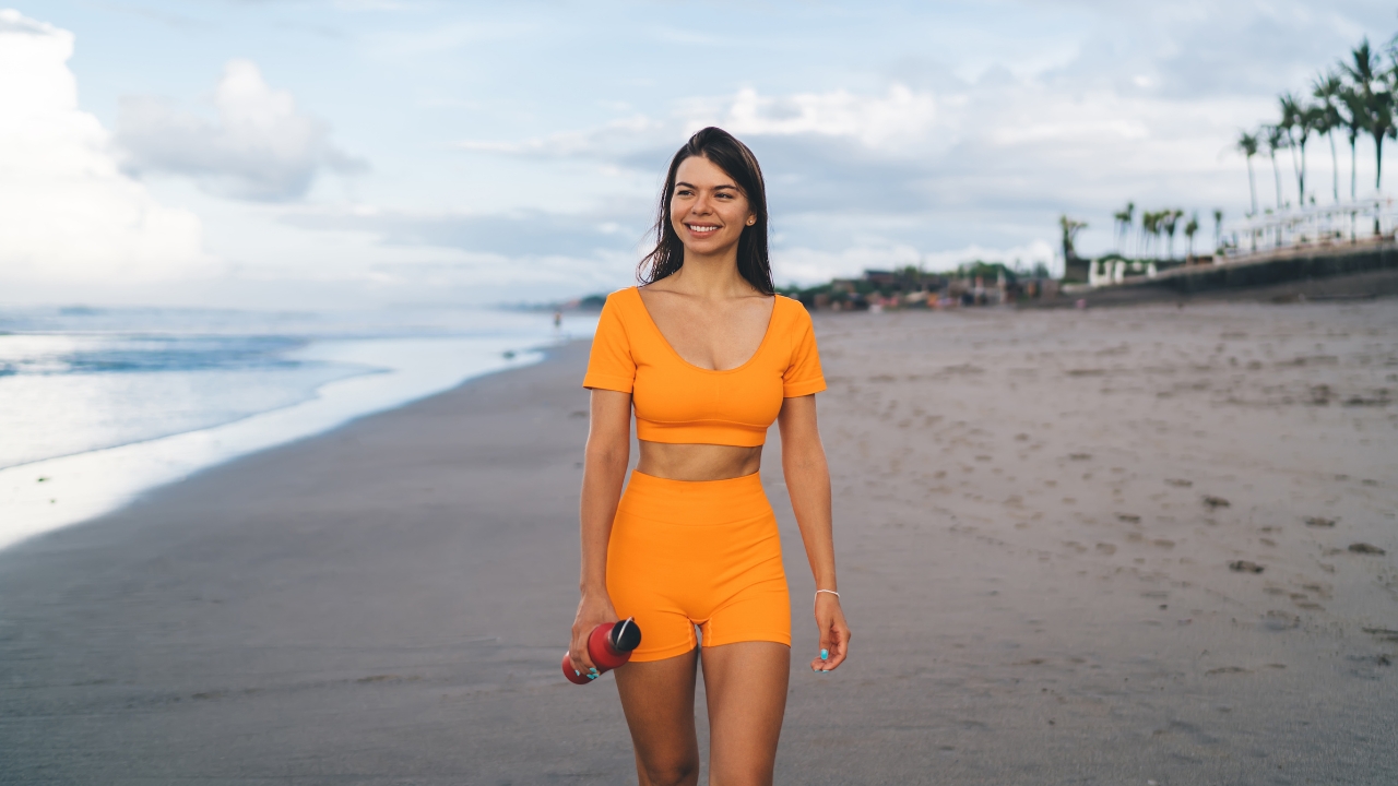 A woman walks on the beach as part of better daily habits for long-term health