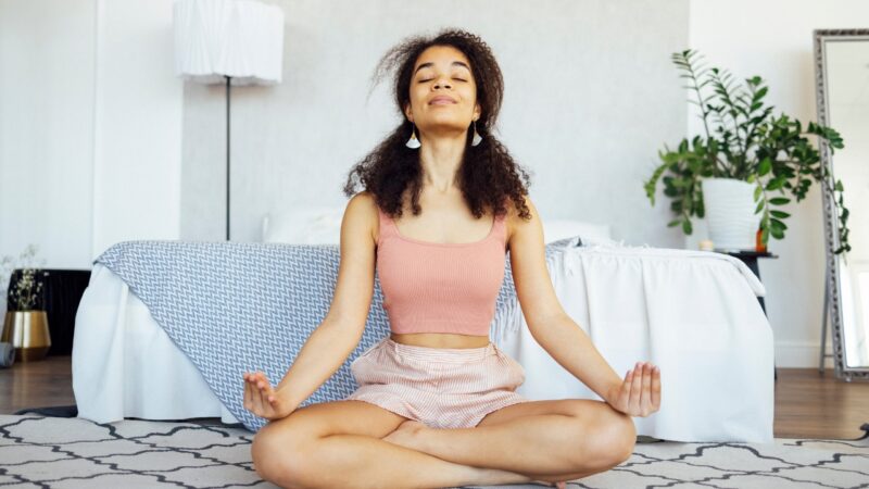 Woman meditates on the floor in a quiet bedroom