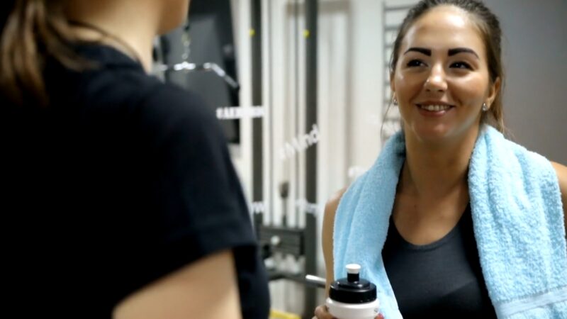 A client smiles as she talks with her fitness trainer after a gym session