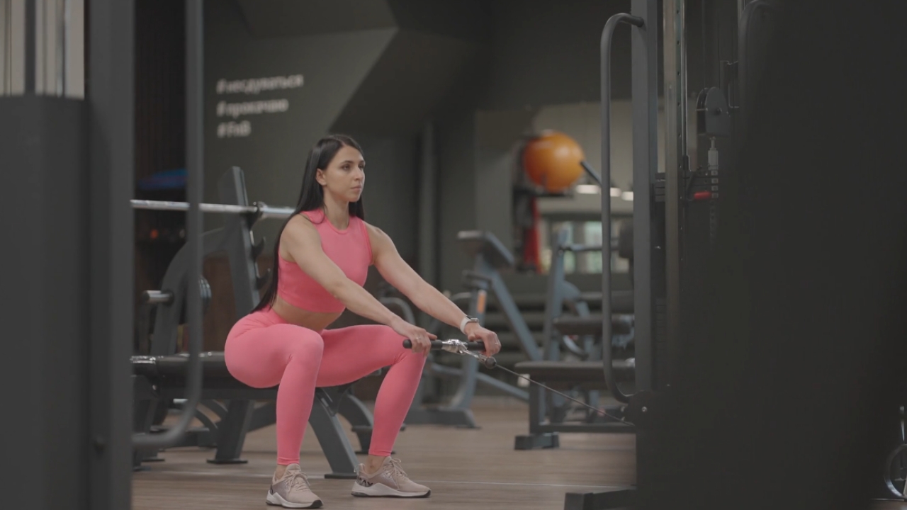 Woman performs a cable squat at the gym