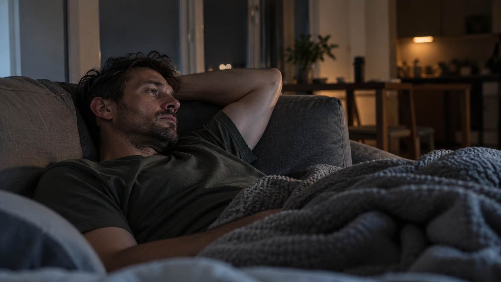 Man lying awake on a couch at night.